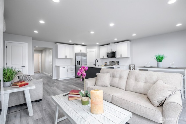 living area with light wood finished floors, baseboards, and recessed lighting