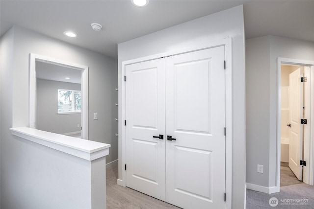 hallway featuring baseboards, recessed lighting, and light colored carpet