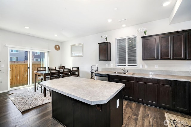 kitchen with a sink, light countertops, stainless steel dishwasher, and dark wood-style flooring