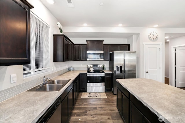kitchen featuring a sink, light countertops, stainless steel appliances, visible vents, and dark wood-style floors