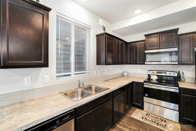 kitchen featuring dark brown cabinets, a sink, light countertops, stainless steel appliances, and backsplash