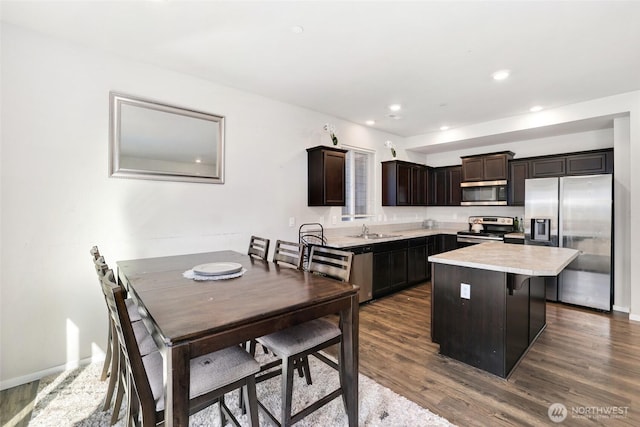 kitchen with dark brown cabinets, dark wood-style floors, light countertops, a sink, and appliances with stainless steel finishes