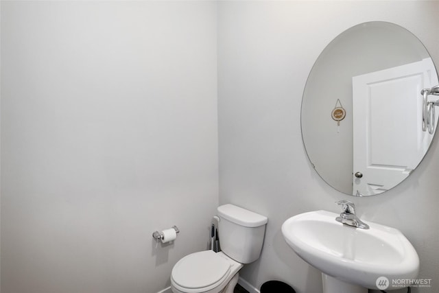half bath with a sink, baseboards, and toilet