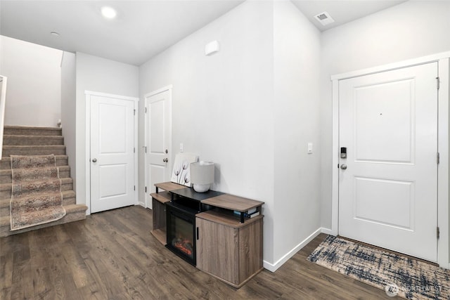 foyer with dark wood-style flooring, baseboards, visible vents, and stairway