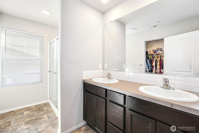 bathroom featuring visible vents, decorative backsplash, a sink, and a stall shower