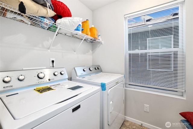clothes washing area with baseboards, laundry area, and washer and clothes dryer