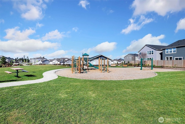 communal playground with a lawn, fence, and a residential view