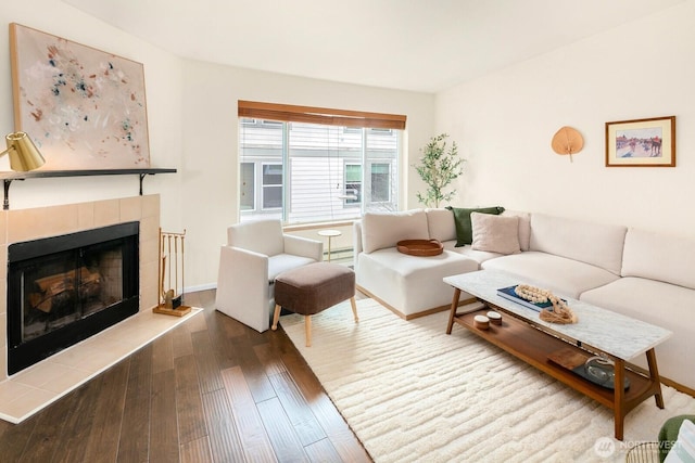 living room featuring a tile fireplace, wood-type flooring, baseboards, and baseboard heating