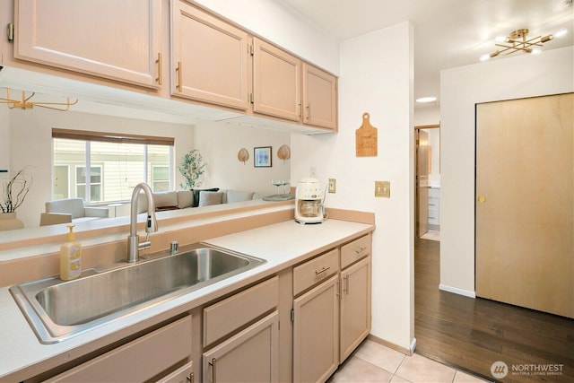 kitchen with light countertops, a sink, baseboards, and light tile patterned floors