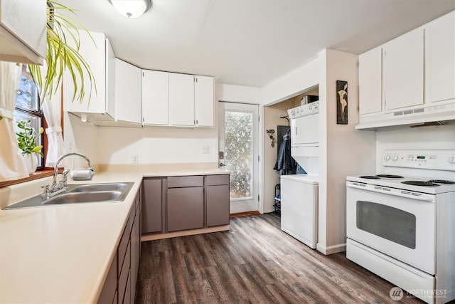10209 Edgewood Dr, Anderson Island, WA 98303 - kitchen with under cabinet range hood, stacked washer / dryer, a sink, white cabinetry, and white range with electric stovetop