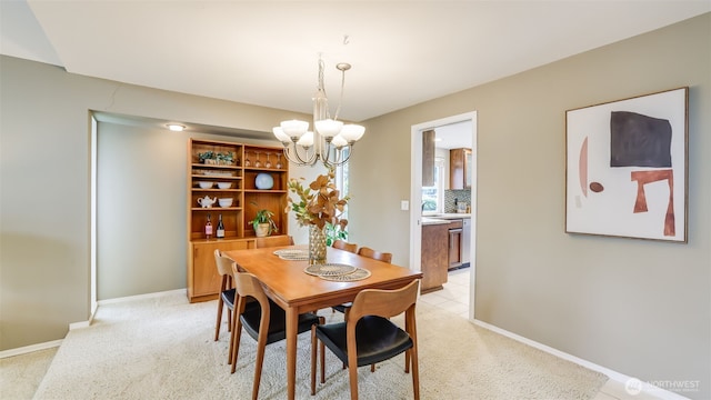 dining space with baseboards, an inviting chandelier, and light colored carpet