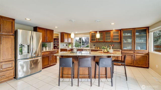 kitchen featuring a kitchen bar, glass insert cabinets, stainless steel refrigerator with ice dispenser, and backsplash