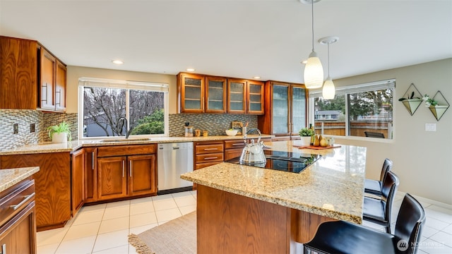 kitchen with brown cabinetry, dishwasher, a sink, and black electric cooktop