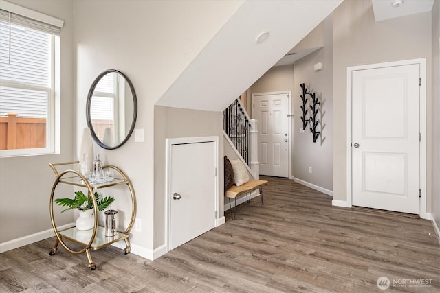 foyer with stairs, wood finished floors, and baseboards