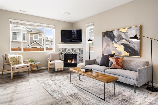 living area with visible vents, a fireplace, baseboards, and wood finished floors