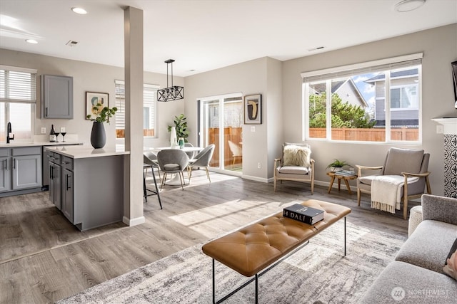 living area featuring visible vents, recessed lighting, light wood-style floors, and baseboards