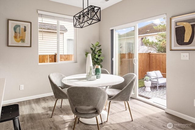 dining room with a chandelier, baseboards, and wood finished floors