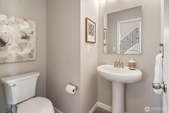 half bathroom featuring a sink, baseboards, and toilet