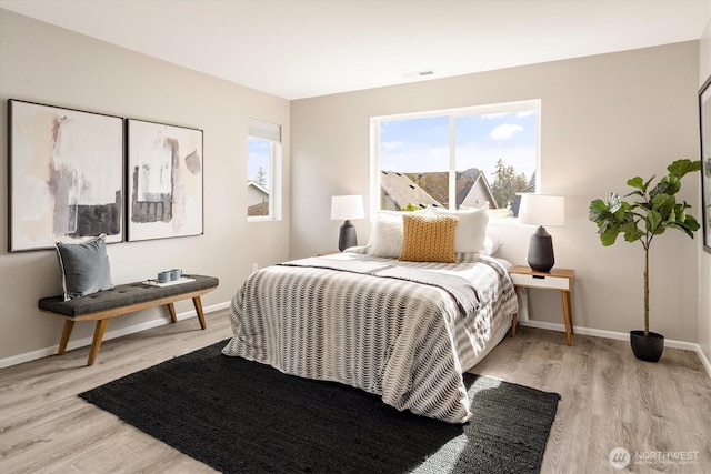 bedroom featuring visible vents, baseboards, and wood finished floors