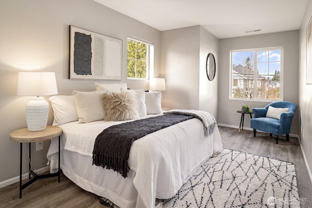 bedroom with visible vents, baseboards, and wood finished floors