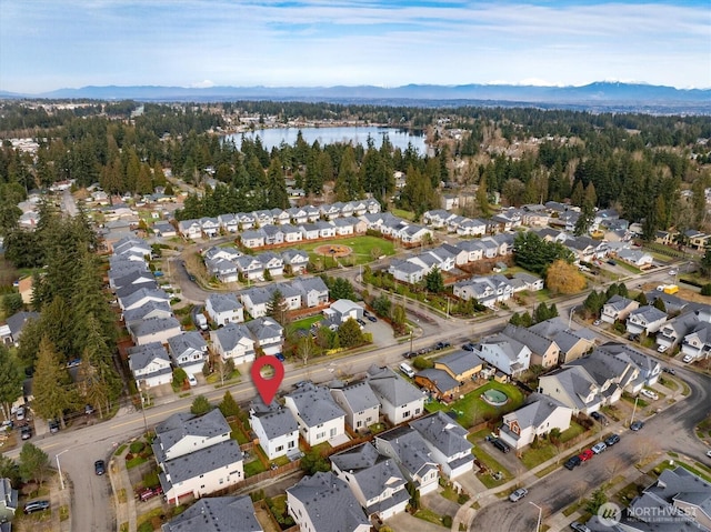 drone / aerial view with a residential view, a wooded view, and a water view