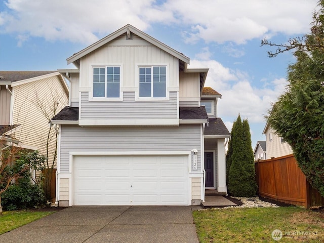 traditional-style house with driveway, a shingled roof, an attached garage, and fence