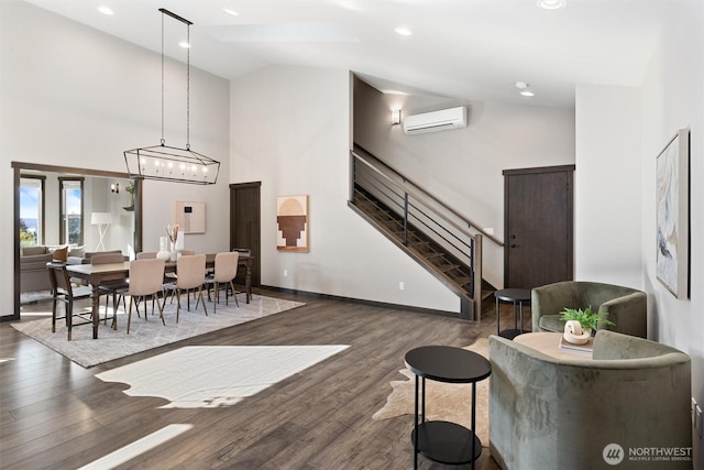 living area with high vaulted ceiling, wood finished floors, baseboards, stairway, and a wall mounted air conditioner