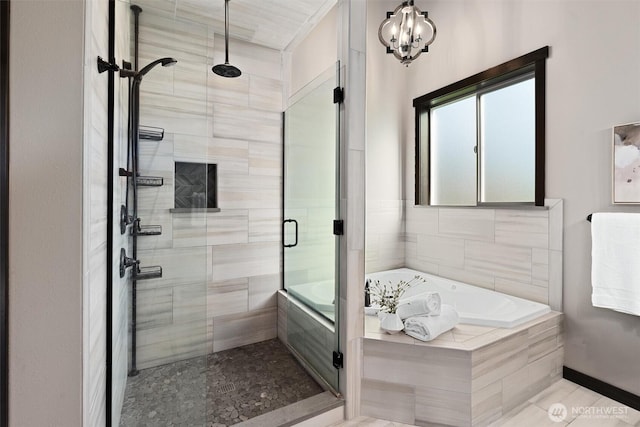 bathroom featuring a shower stall, an inviting chandelier, and a bath