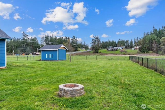 view of yard featuring a storage shed, an outbuilding, a fenced backyard, and a fire pit