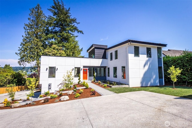 modern home with fence, a front lawn, and stucco siding