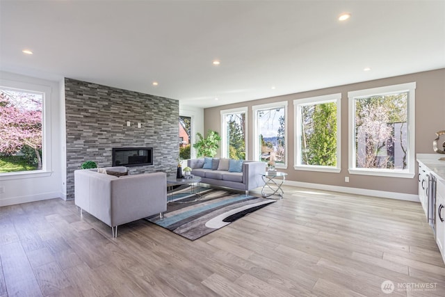 living area with recessed lighting, a healthy amount of sunlight, a fireplace, and light wood finished floors