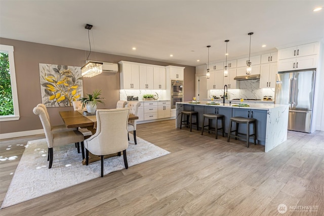 dining area with baseboards, a wall mounted AC, light wood-style flooring, and recessed lighting