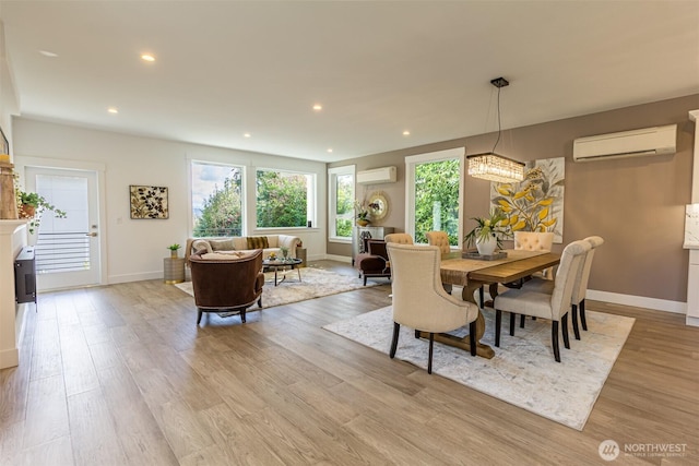 dining space with light wood-type flooring, a healthy amount of sunlight, a wall unit AC, and a wall mounted AC