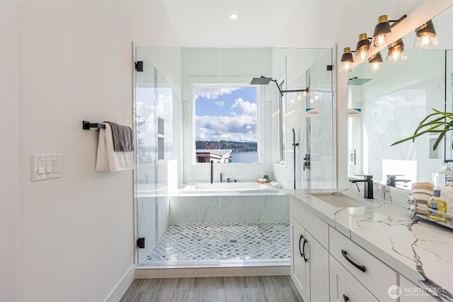 full bathroom featuring wood finished floors, vanity, a marble finish shower, and a bath