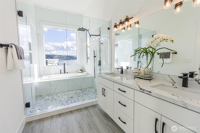 full bath with double vanity, wood tiled floor, a marble finish shower, and a sink