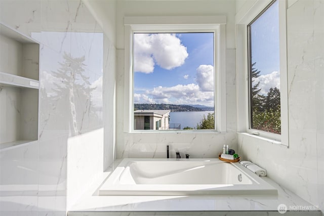 full bathroom with a water view and a tub with marble appearance