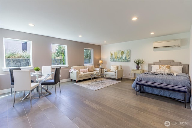 bedroom featuring recessed lighting, an AC wall unit, baseboards, and wood finished floors