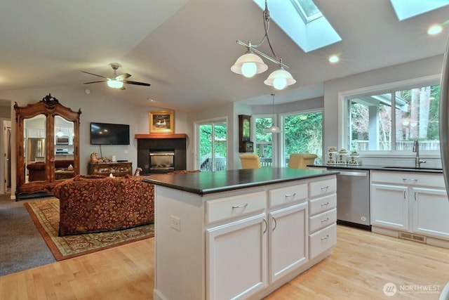 kitchen featuring a sink, dark countertops, lofted ceiling with skylight, and stainless steel dishwasher