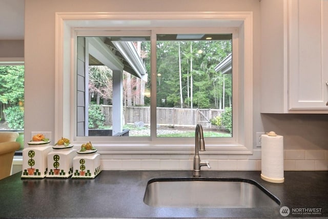 interior details featuring dark countertops, a sink, and white cabinetry