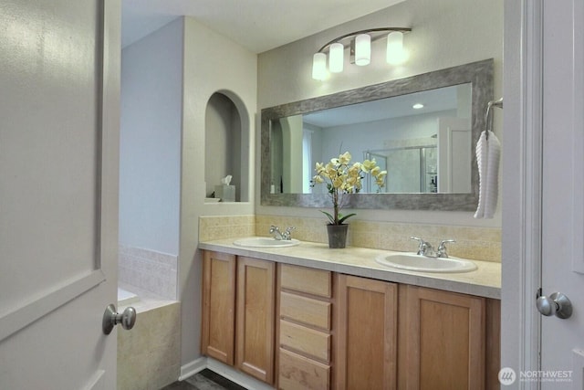 full bathroom with double vanity, a sink, a bathing tub, and a shower stall