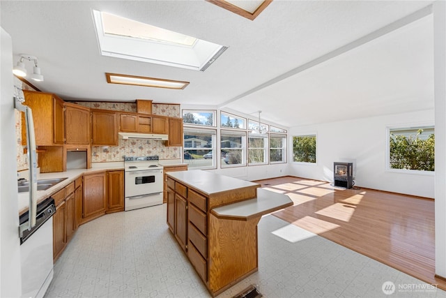2308 Vista Ln, Anacortes, WA 98221 - kitchen with white appliances, lofted ceiling with skylight, a wood stove, light countertops, and under cabinet range hood