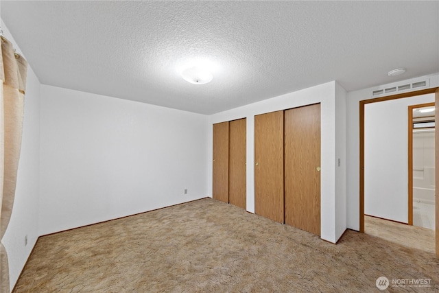 2308 Vista Ln, Anacortes, WA 98221 - unfurnished bedroom featuring a textured ceiling, carpet, visible vents, and multiple closets