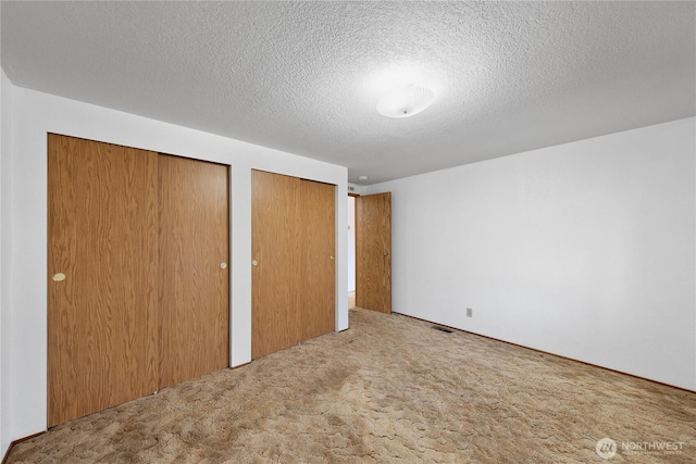 2308 Vista Ln, Anacortes, WA 98221 - unfurnished bedroom with a textured ceiling, visible vents, two closets, and carpet flooring