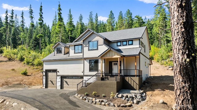 view of front facade featuring a garage, a forest view, aphalt driveway, and roof with shingles