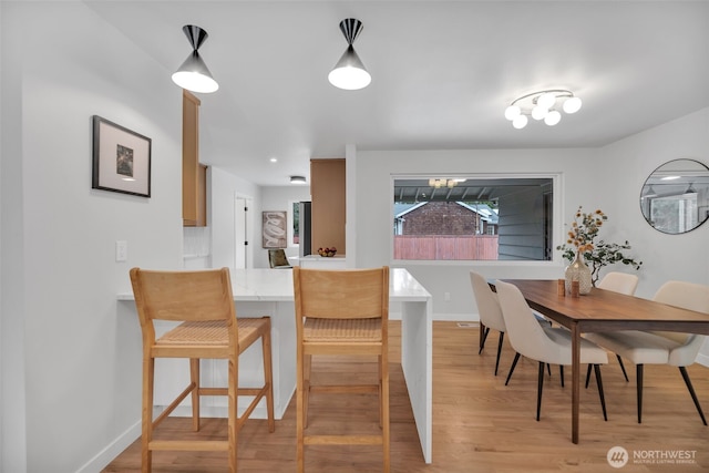 dining space featuring baseboards and light wood-style floors