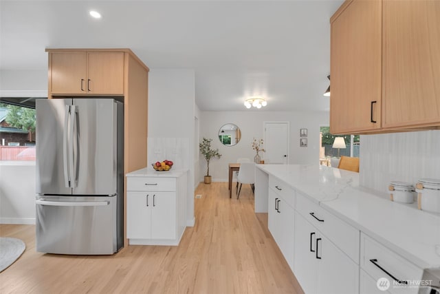 kitchen featuring light wood-style floors, freestanding refrigerator, plenty of natural light, and light stone counters