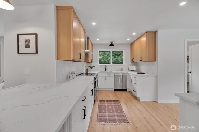 kitchen with a sink, light stone countertops, stainless steel appliances, and backsplash