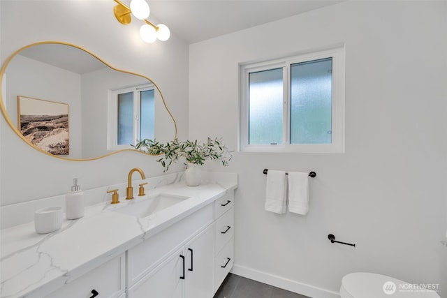 bathroom with toilet, vanity, and baseboards