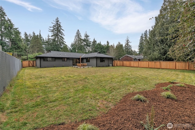 rear view of house with a fenced backyard and a yard