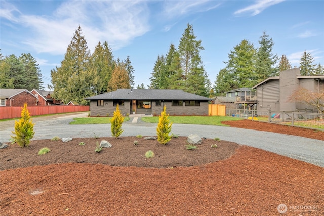 view of front of property with stone siding, driveway, and fence